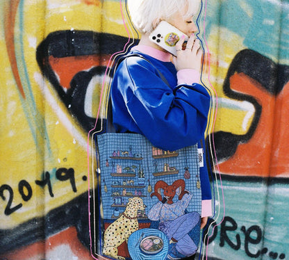 Person standing in front of colorful graffiti wall wearing blue jacket with white stripes on sleeves and blue bag with cartoon characters including yellow leopard, blue cat, and red dog.