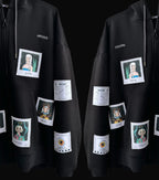 A black hoodie with multiple patches of different sizes and shapes scattered all over it. The patches have different designs on them, including cartoon characters, photographs, and text. The hoodie has a zipper in the front and a hood with drawstrings.