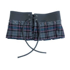 A cropped plaid mini skirt with a wide gray waistband, lace-up front, and pleated flared skirt, shown on a solid black background.