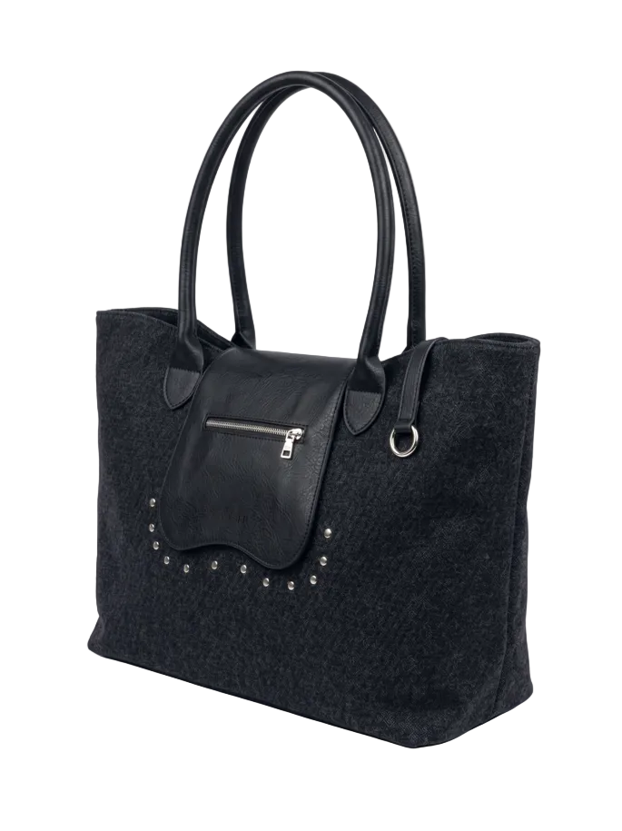 A black canvas tote bag with smooth black leather handles, a front zippered pocket, and silver-tone studs, shown on a light gray background.