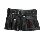 A black patent leather mini skirt with a wide belt featuring a large silver-tone ring buckle, side grommets, a small keychain detail, and a front pocket with 'ORASHI' branding.