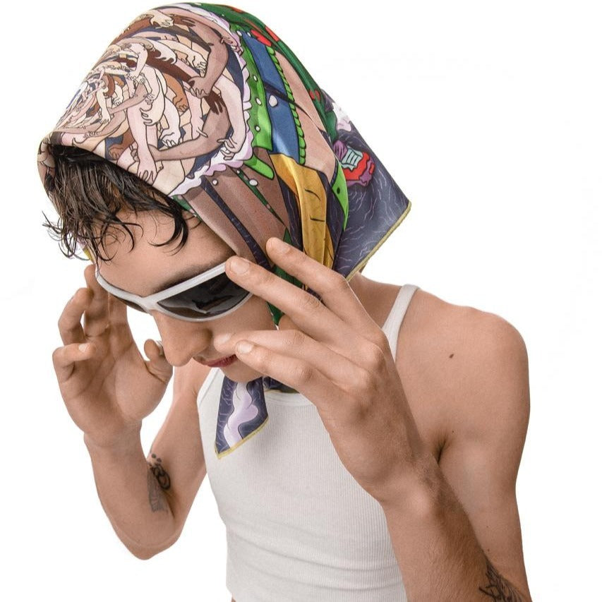 A person wearing a colorful bandana on their head and a white tank top. The bandana is a mix of colors and patterns, including orange, green, blue, and yellow. The person’s face is blurred to protect their privacy. The person has a tattoo on their left arm. The background is white.