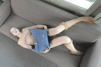 Model in a nude bodysuit lying on a grey sofa with the Omashu Ines blue denim key pocket bag styled as a crossbody.