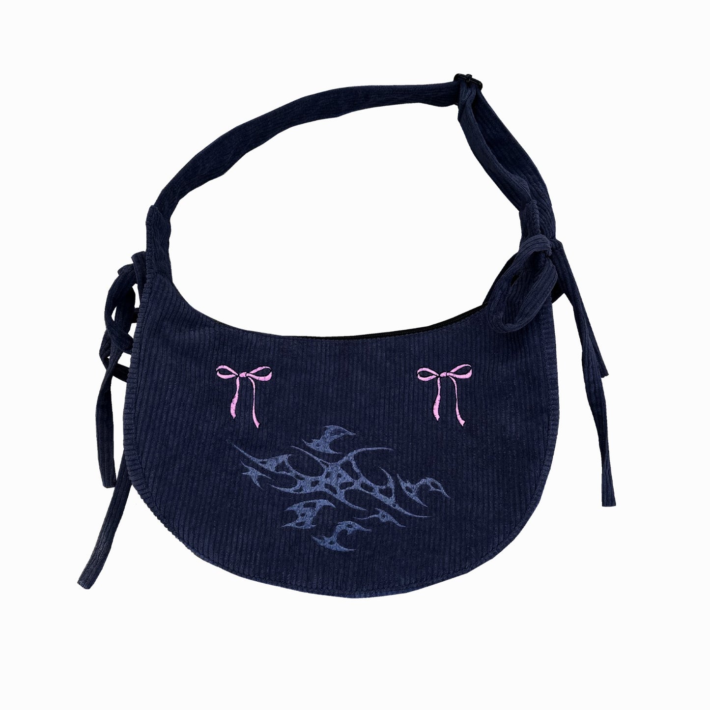 A dark corduroy shoulder bag with pink embroidered bows and a tribal design, displayed against a white background. The bag features a tied strap on each side, adding to its casual, feminine appeal.