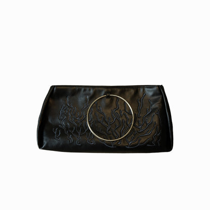 Black bag features a circular and wavy metallic embellishment on the front. Made from faux leather material.