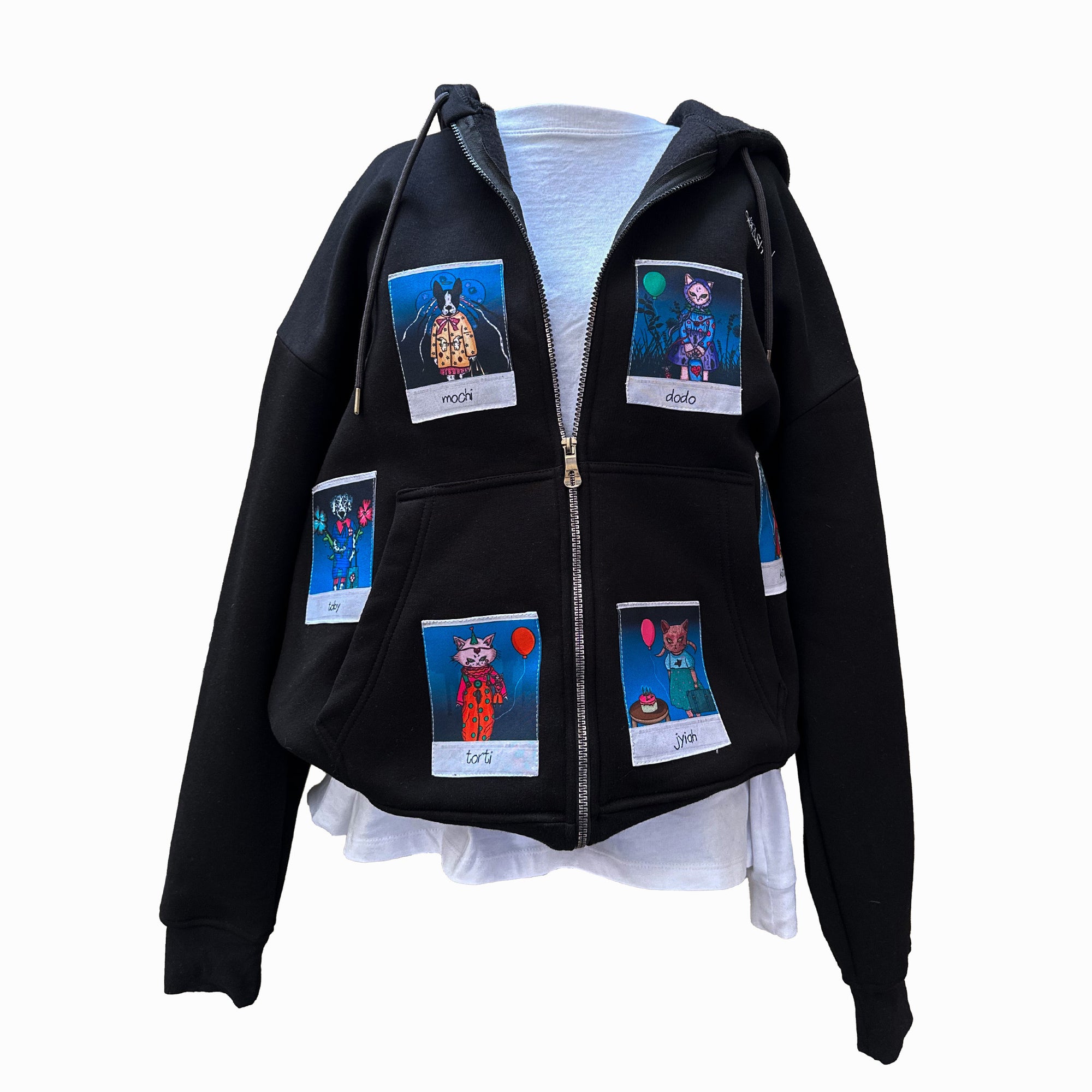 A black zip-up hoodie displayed on a mannequin, featuring six colorful Polaroid-style patches of animal characters. The characters include "Mochi," "Dodo," "Torti," "Jiyah," "Toby," and another on the back. The hoodie is shown with the zipper open, revealing a white inner layer underneath.