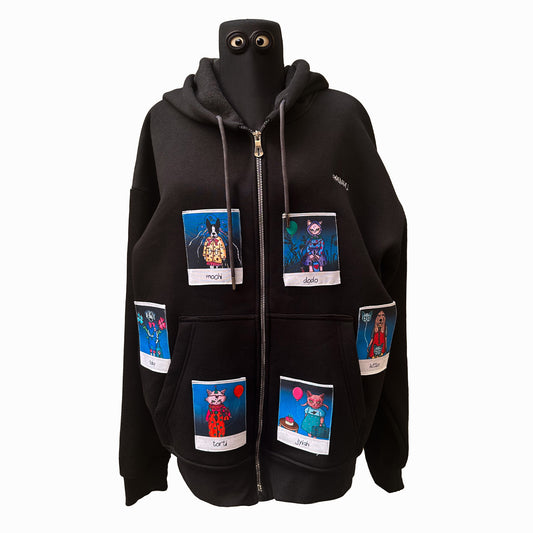 A black zip-up hoodie adorned with colorful Polaroid-style patches of animal characters. The characters include "Mochi," "Dodo," "Torti," "Jiyah," "Toby," and "Kittie," each with their own unique accessories like balloons and cakes. The hoodie is displayed on a mannequin with the zipper partially open, showcasing the vibrant patches on the front.