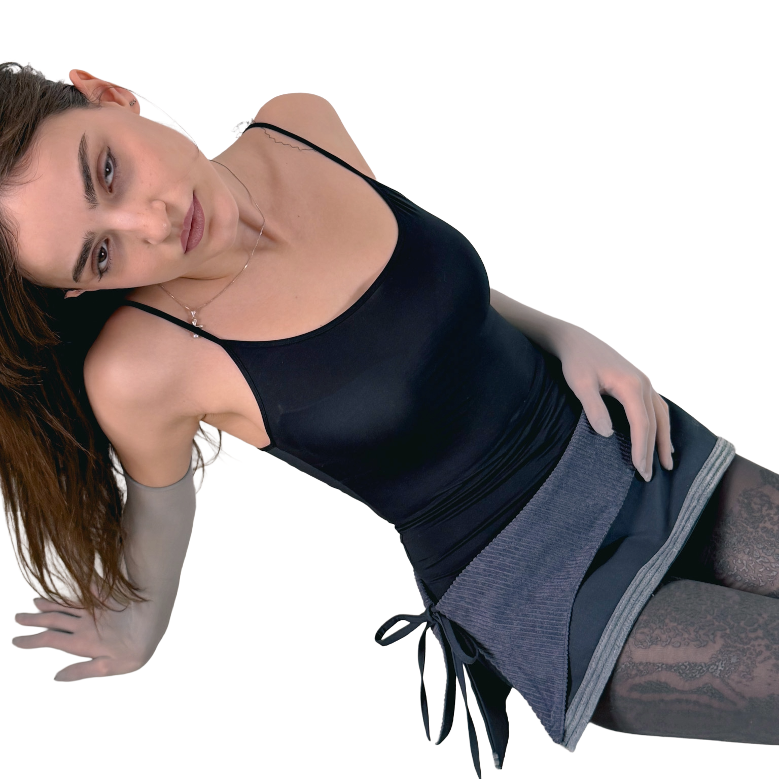 Woman wearing a black tank top and gray skirt on a white background