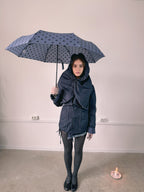 Person holding a dark blue umbrella with white polka dots indoors.