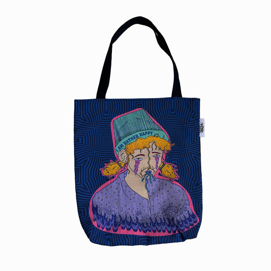 An Omashu tote bag with a graphic design of a man with a beard and a hat that reads ‘I'm Rather Happy’, wearing a purple shirt and orange tassels, against a blue geometric pattern background, with a black handle and a white tag on the top right corner 'OMASHU'.