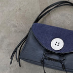 Blue handbag with black fringes on a concrete floor