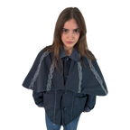 Person wearing a dark blue cape with braid details on a white background