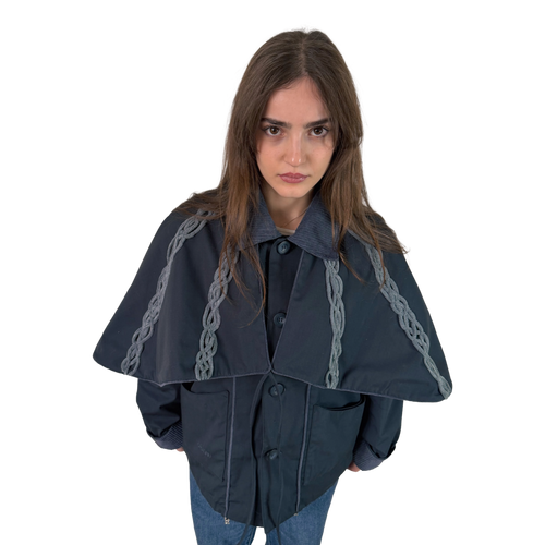 Person wearing a dark blue cape with braid details on a white background