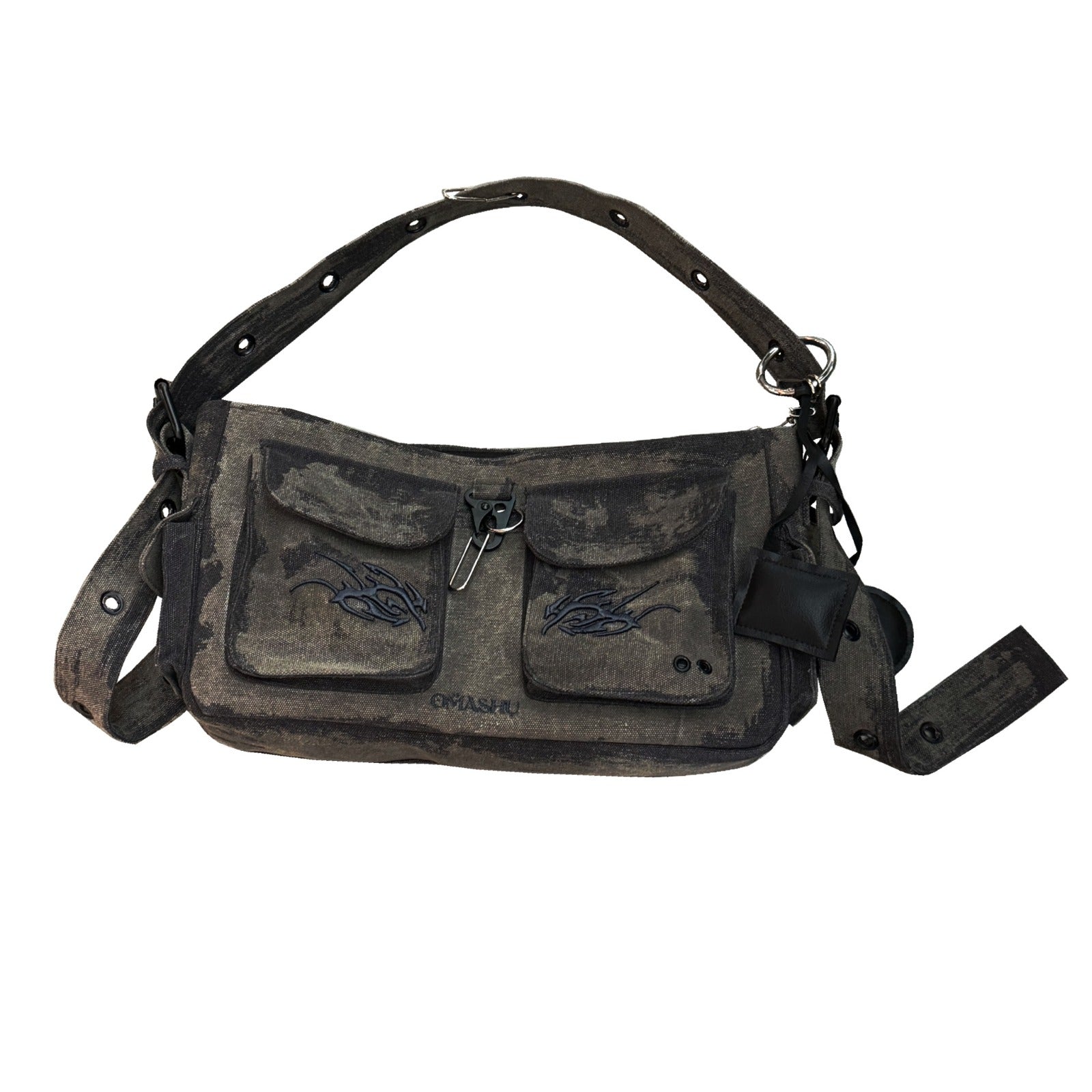 A dark gray canvas shoulder bag with a rugged, worn look, featuring two front pockets with flap closures and black embroidery designs on each pocket. The bag has an adjustable strap with metal eyelets and buckle details. A small black leather attachment hangs from one side of the bag, adding to its utilitarian aesthetic.