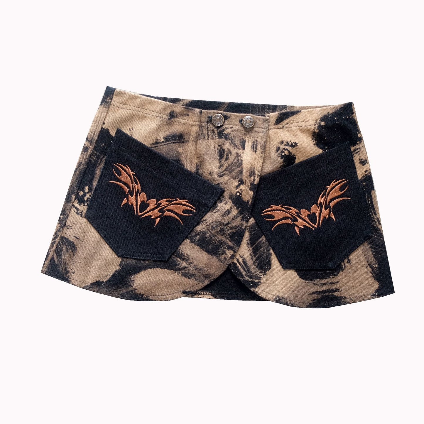 This skirt combines trouser and belt aesthetics. It has a camouflage pattern and orange floral embroidery on the back pockets. The button and zipper closure add to its unique style.