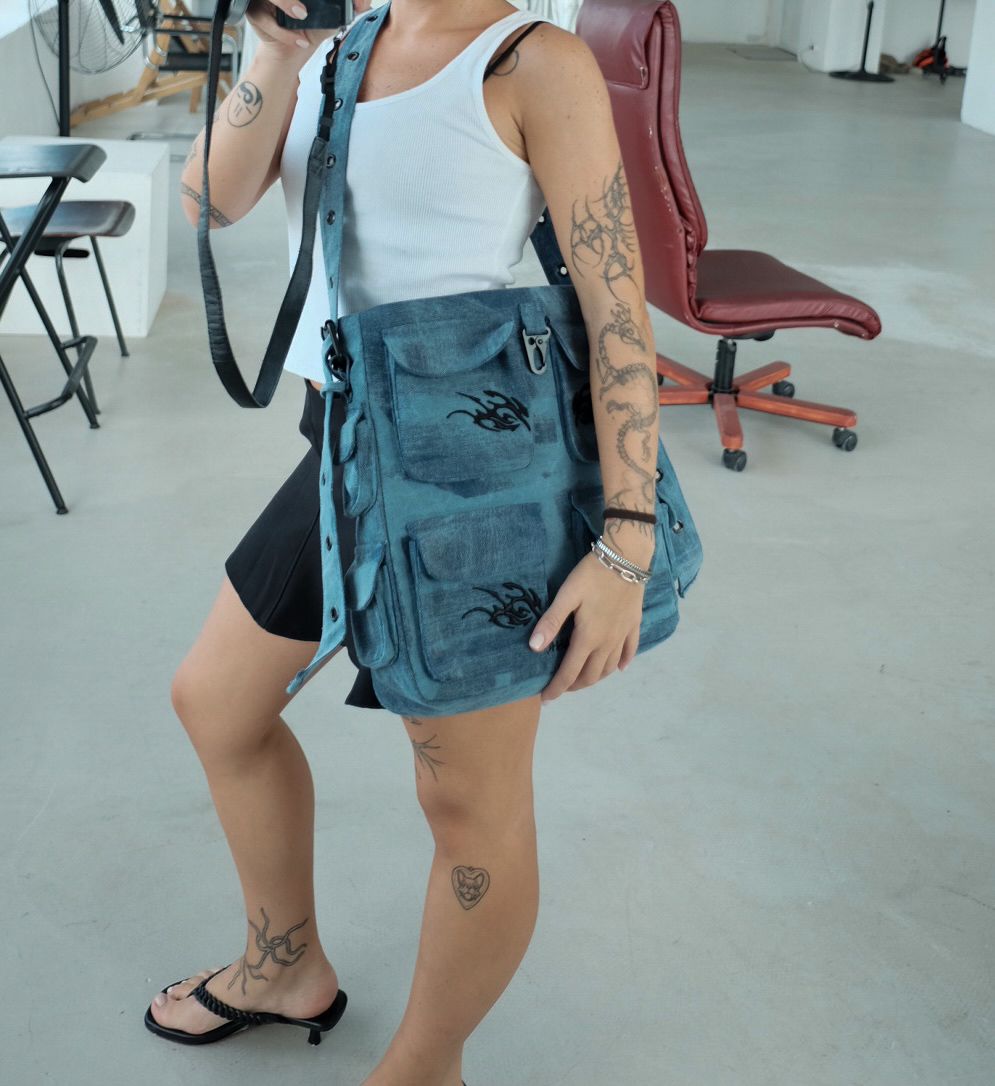 Person carrying the Keychain Cargo Bag XL - Ocean, featuring a casual denim look with tribal designs.