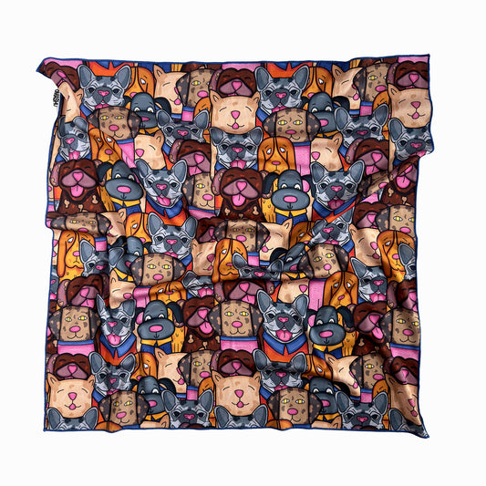 A square scarf with a repeating pattern of cartoon dogs. The dogs are in different colors and poses, with some wearing cloth. The background is a light color. The pillow has a white border.