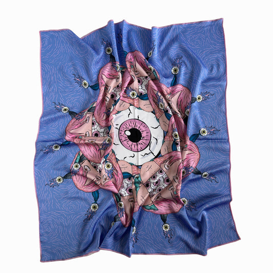 A blue silk scarf with a pink and white design in the center. The design in the center is an eye with long eyelashes and a pink iris. The eye is surrounded by pink and white flowers and leaves. The scarf is folded in a way that the design is in the center and the blue silk is on the outside.