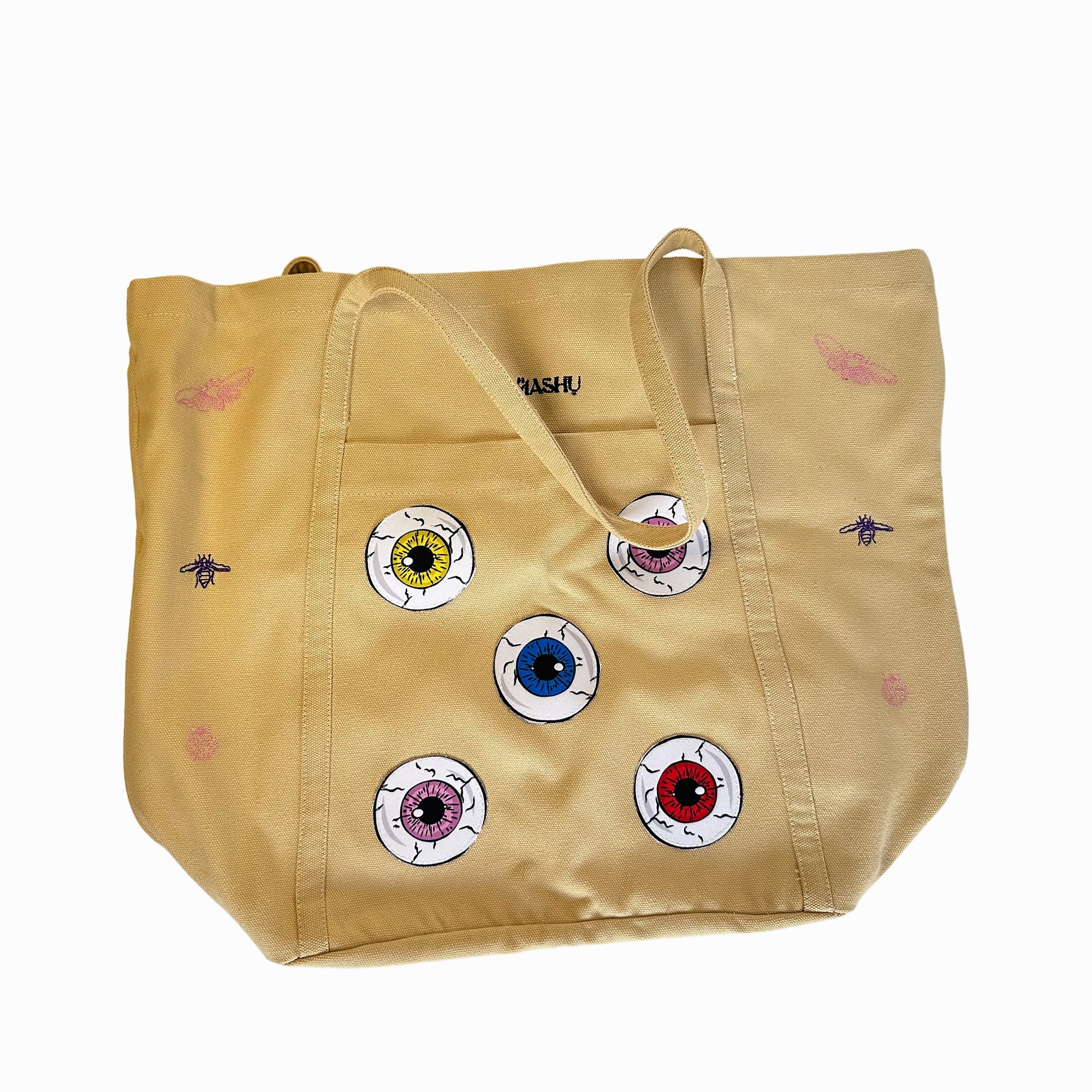 OMASHU brand beige tote bag with colorful eyeball designs and emroidered accents.