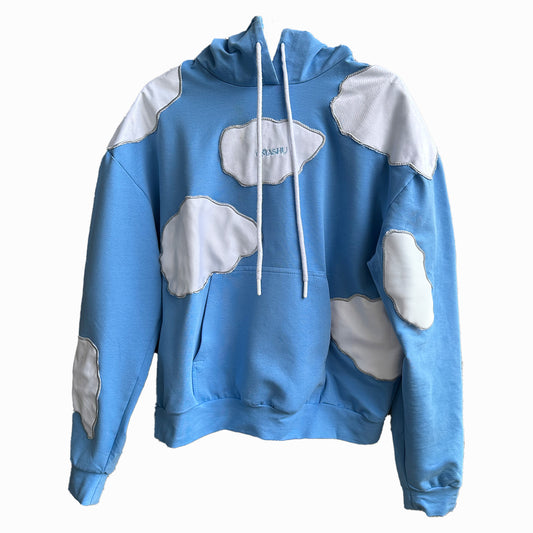 Blue hoodie with white patches on sleeves, chest, and stomach area with white drawstring and white label on chest that reads ‘OMASHU’ on white background.