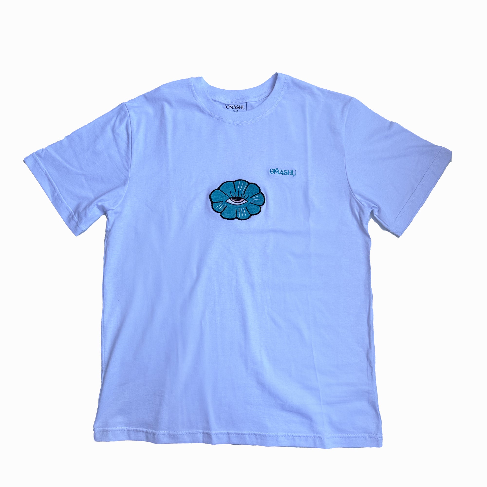 a t-shirt with flower design. The flower design is a simple line drawing of teal flower with five petals and eye inside. The word “Omashu” is written in cursive above the flower design. The t-shirt is white ,short-sleeved and has a crew neck.