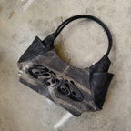 Black handbag with a brand logo on a concrete floor