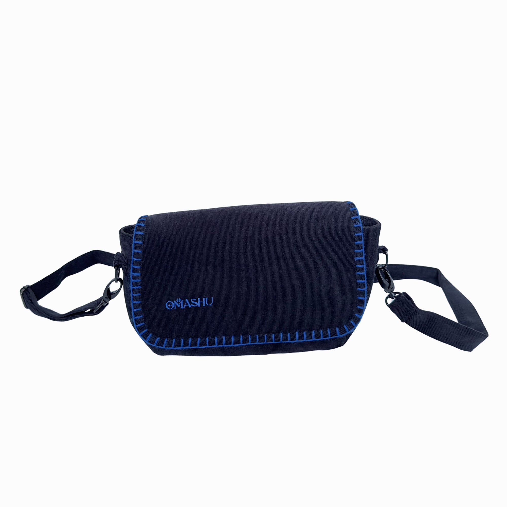 A photo of a black OMASHU crossbody bag with blue stitching, featuring a flap closure with a blue border, a black adjustable shoulder strap, and a small white logo on the flap that reads ‘OMASHU’.