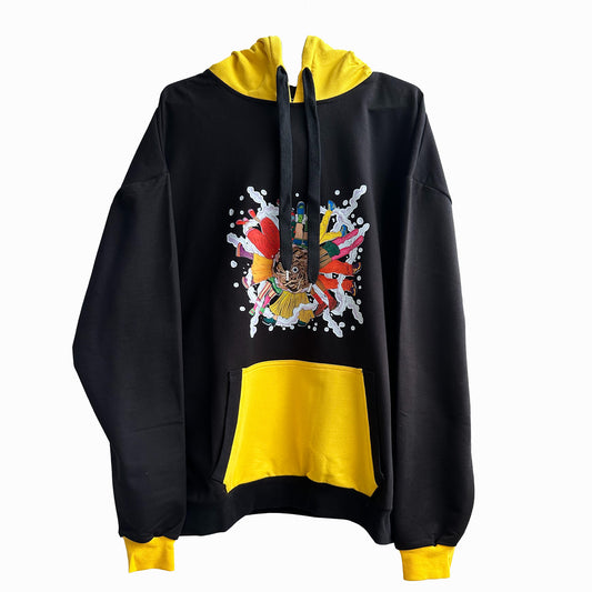 A black and yellow hoodie with a colorful graphic on the front. The hoodie has a black body and yellow sleeves and hood. The graphic on the front is a colorful explosion of flowers, leaves, and paint splatters. The graphic also includes a hand holding a paintbrush and a bird. The hoodie has a drawstring hood and a front pouch pocket. The background is white.