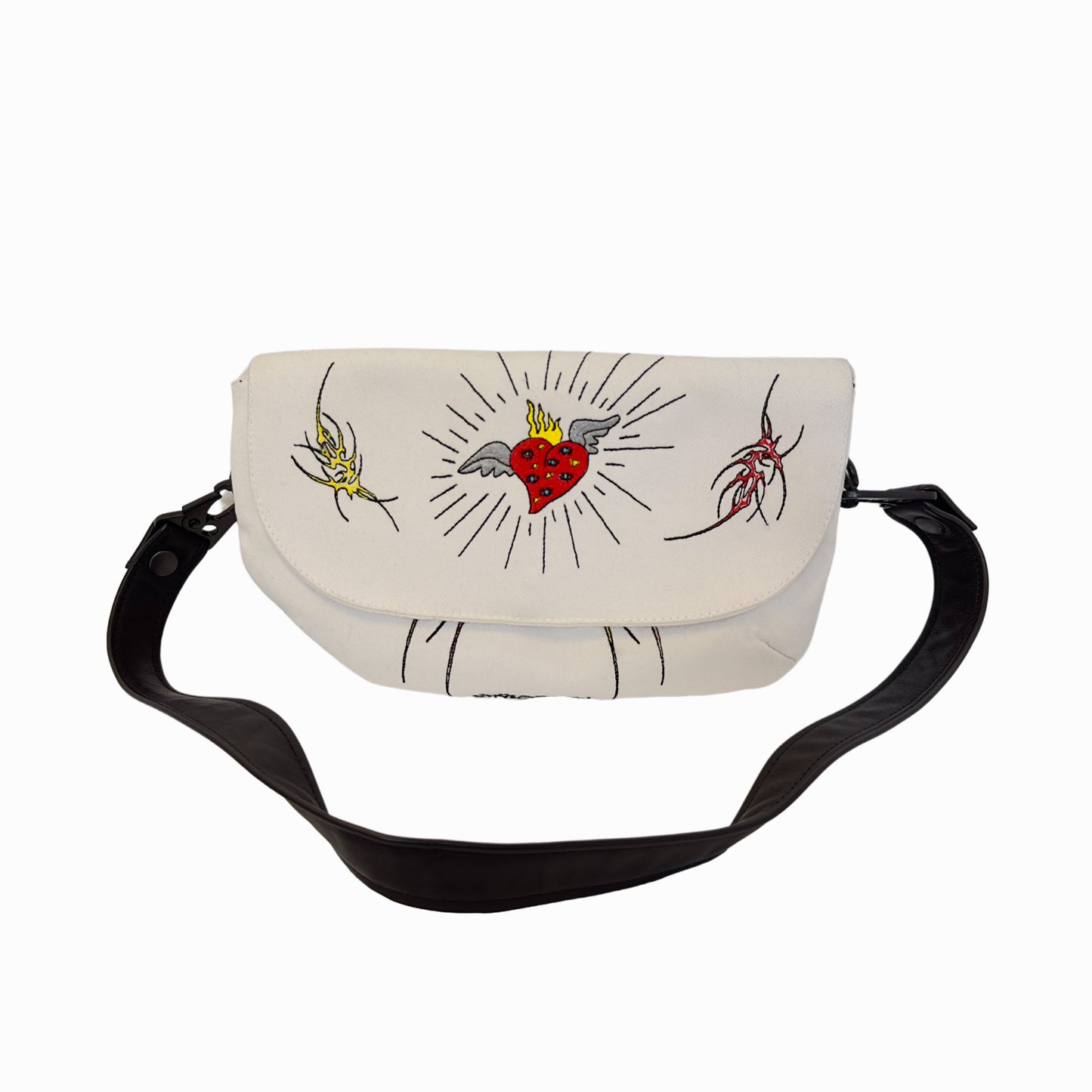 A white crossbody bag with a black strap. The bag has three illustrations on it - a yellow and red on sides, a red heart in the center. The strap is black and appears to be made of leather. The background is plain white.